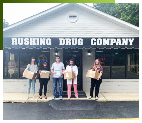 Employees and the pharmacist stand in front of Rushing Drug Company with DisposeRx drug disposal packets
